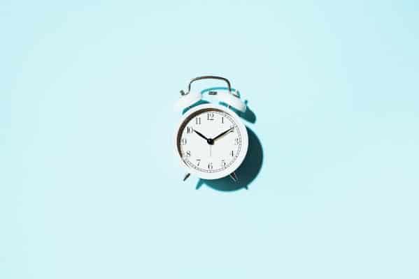 Afkomen van je Suikerverslaving: tips 4 white alarm clock with hard shadow on blue backgro EM9BJ5L